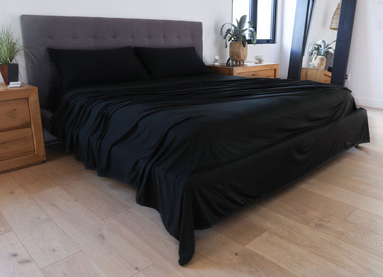 Black sheet set shown on bed in bedroom environment. #choose-your-color_black