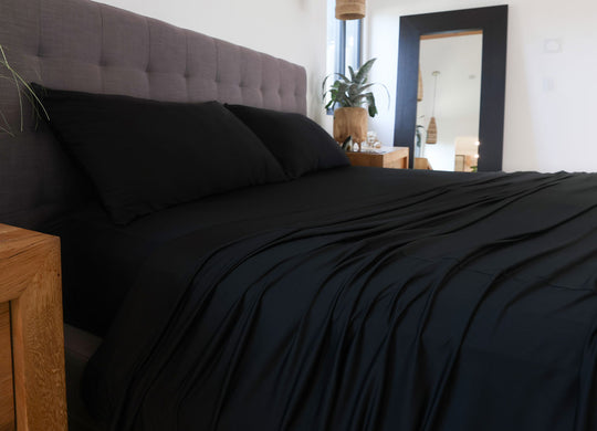 Black sheet set shown on bed in bedroom environment. #choose-your-color_black