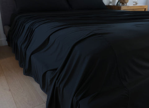 Black sheet set shown on bed in bedroom environment. #choose-your-color_black